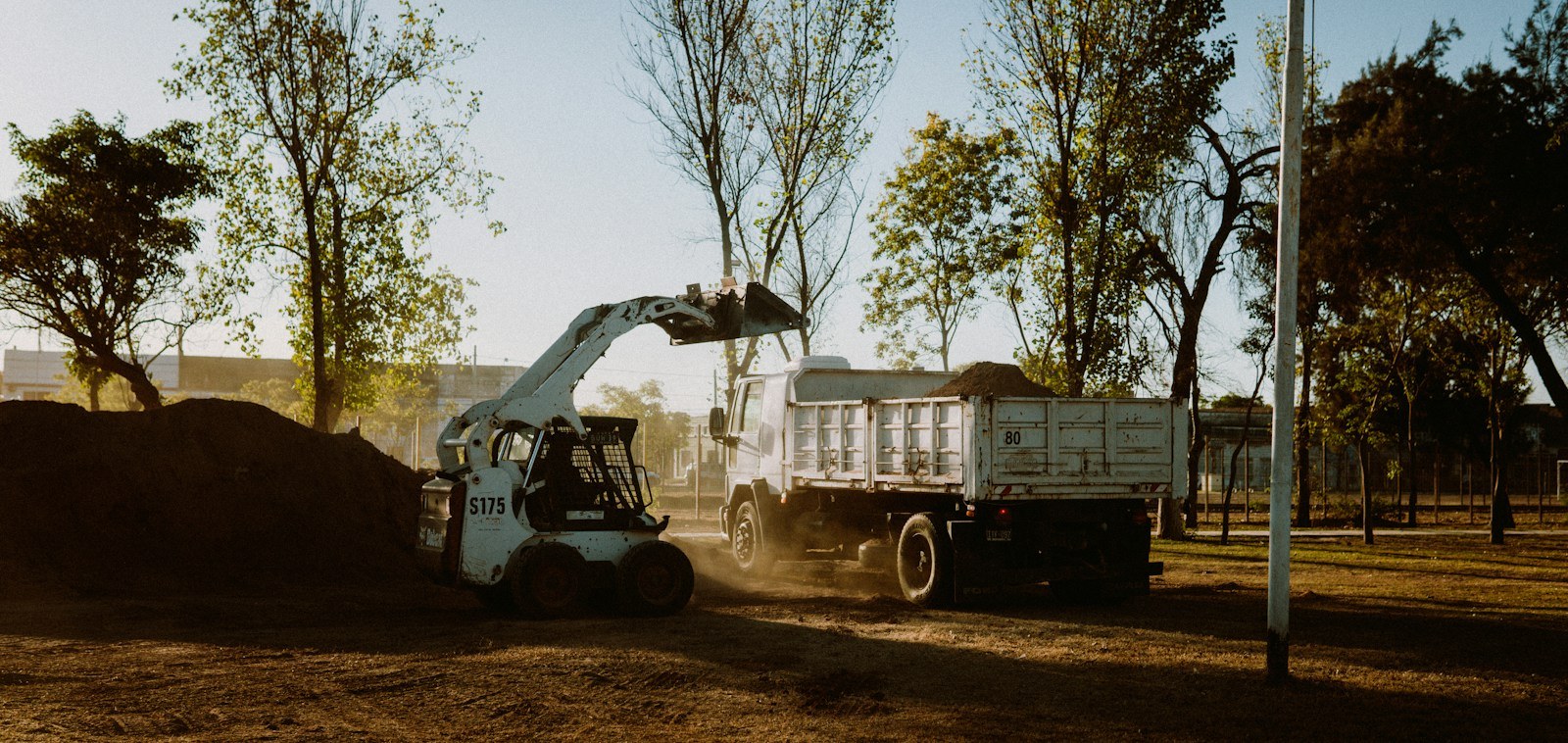 Skid steer moving material into a truck at a rural work site